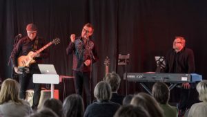 Rust med Tom Wangerud holder motivasjonsforedrag. med livemusikk